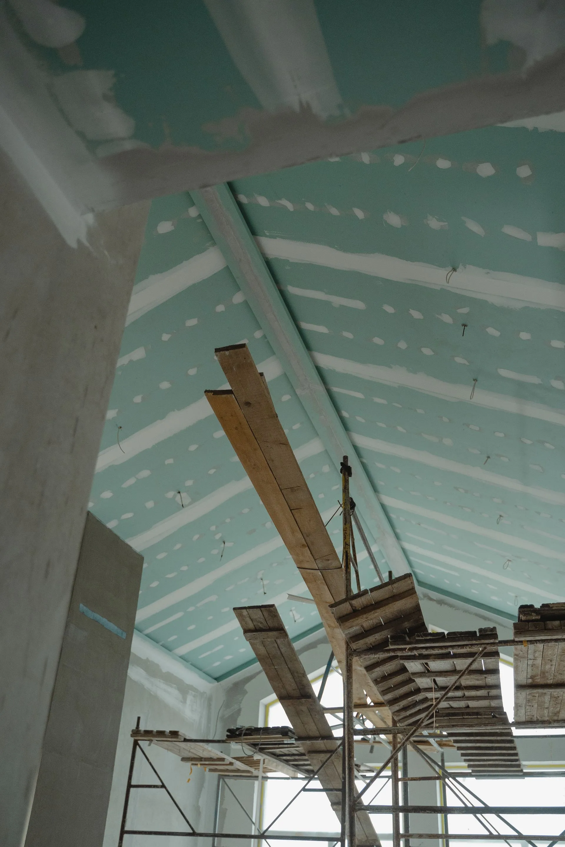 Plafond rampant en plaques de plâtre en cours de jointoiement sur un chantier de rénovation